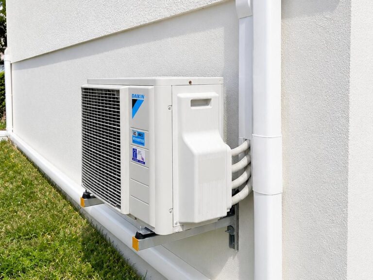 Unité extérieure Daikin murale avec goulottes blanches sur façade crépi