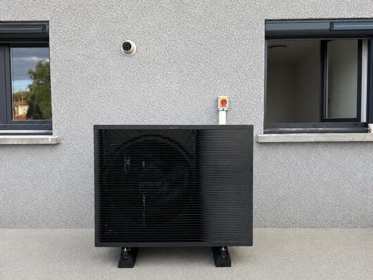 Pompe à chaleur Daikin anthracite entre deux fenêtres sur crépi clair