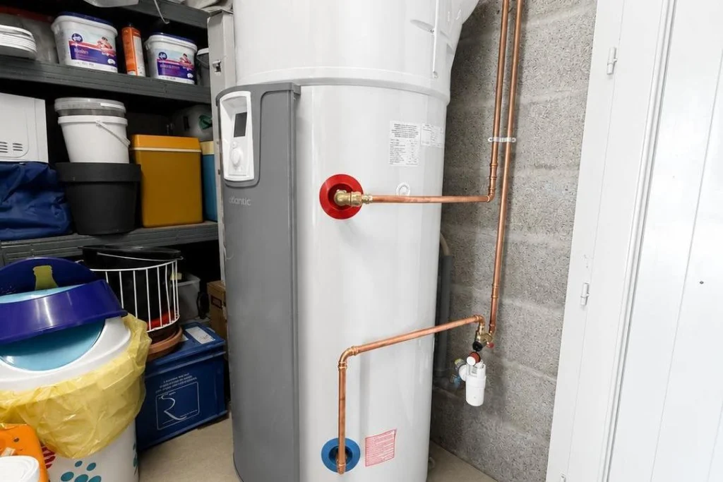 Chauffe-eau thermodynamique installé dans un garage, raccordé par des tuyaux en cuivre avec son groupe de sécurité