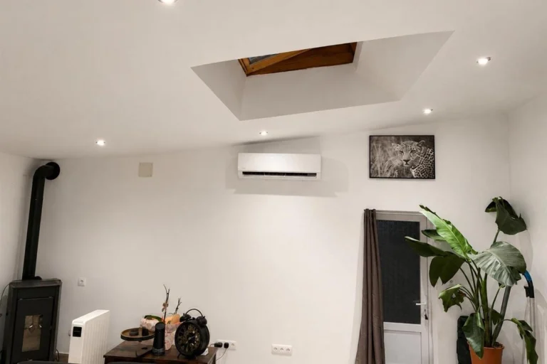 Séjour sous combles équipé d'une unité murale de climatisation réversible, avec un poêle à gauche et un radiateur électrique au sol