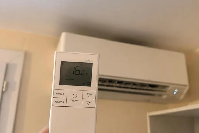 Télécommande de climatisation affichant une consigne de 16 °C en mode froid, devant une unité intérieure murale