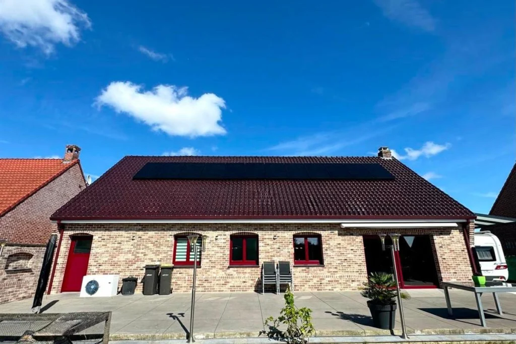 Maison en briques équipée de panneaux photovoltaïques en toiture et d'une unité extérieure de pompe à chaleur au pied de la façade